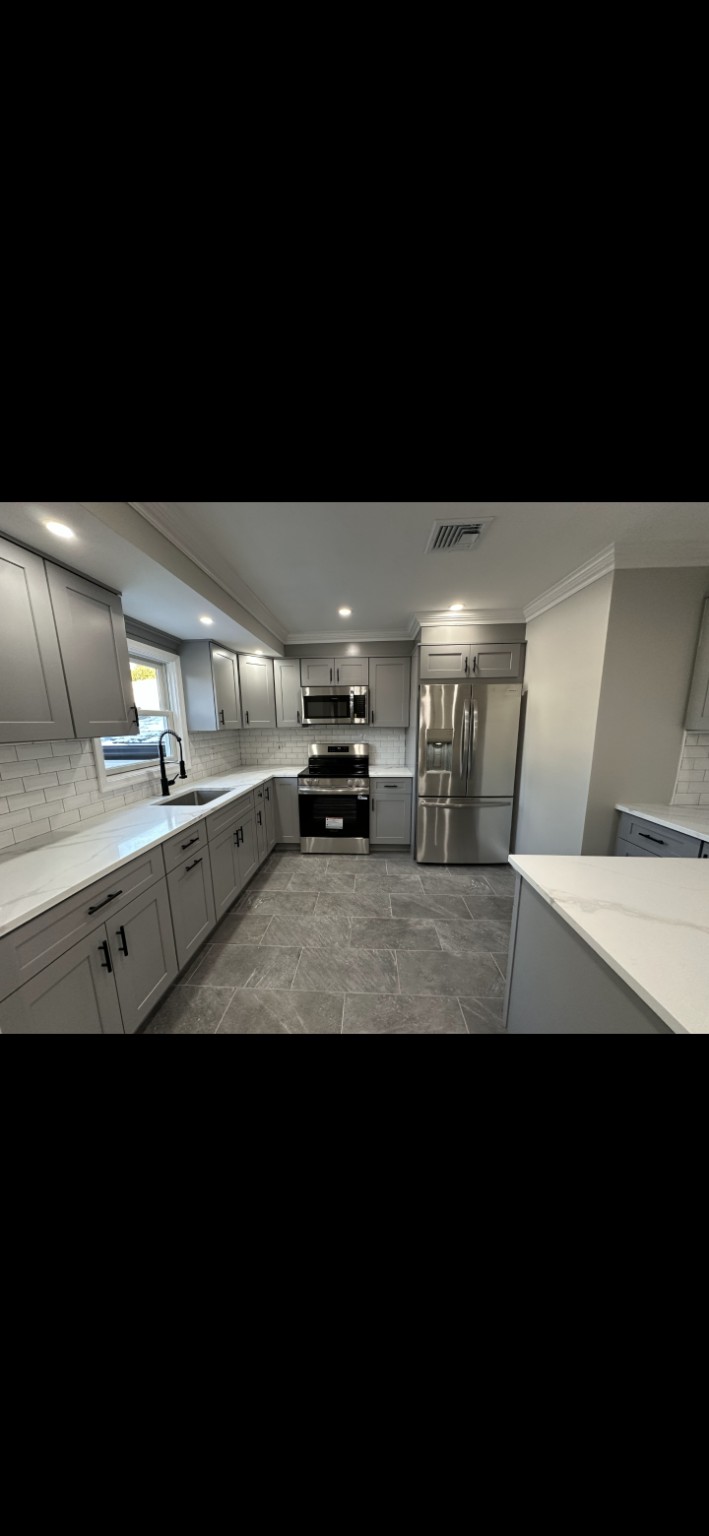 Completed grey Shaker kitchen with white countertops, subway tile backsplash and island