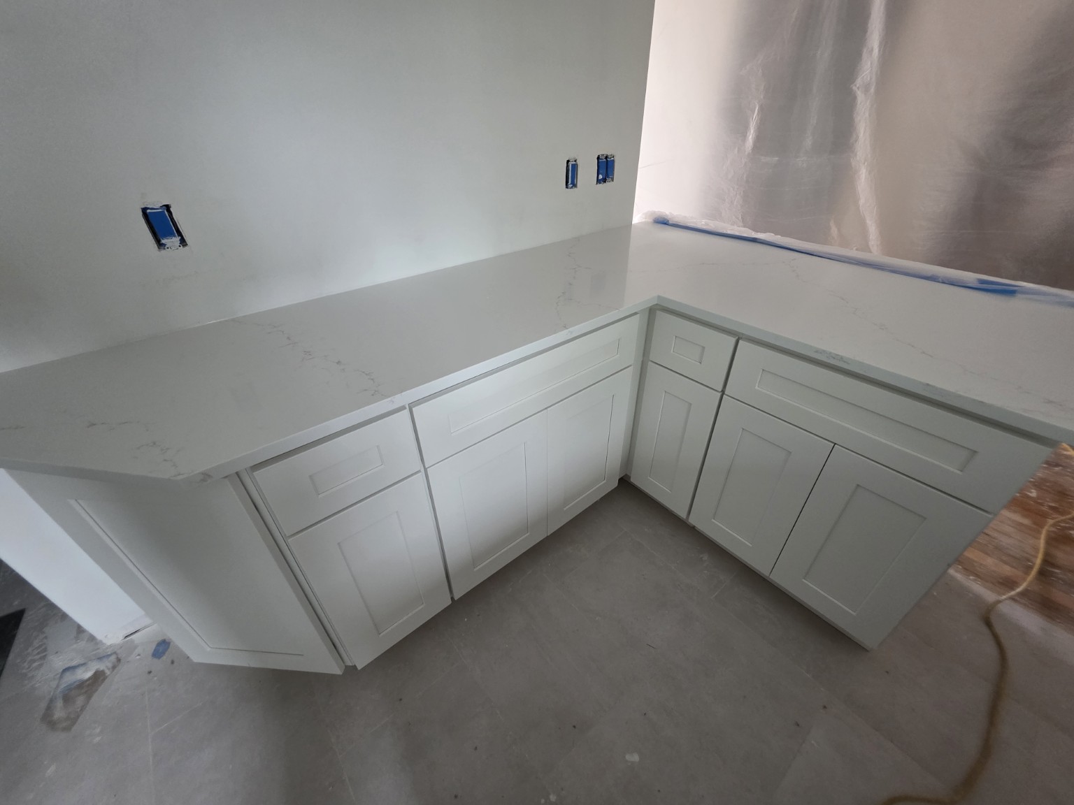 Completed white Shaker base cabinets with quartz countertop and backsplash