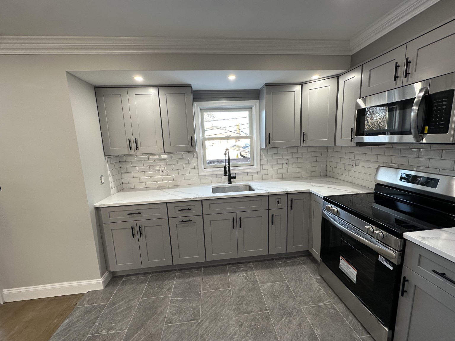 Completed grey Shaker kitchen with subway tile backsplash and stainless appliances