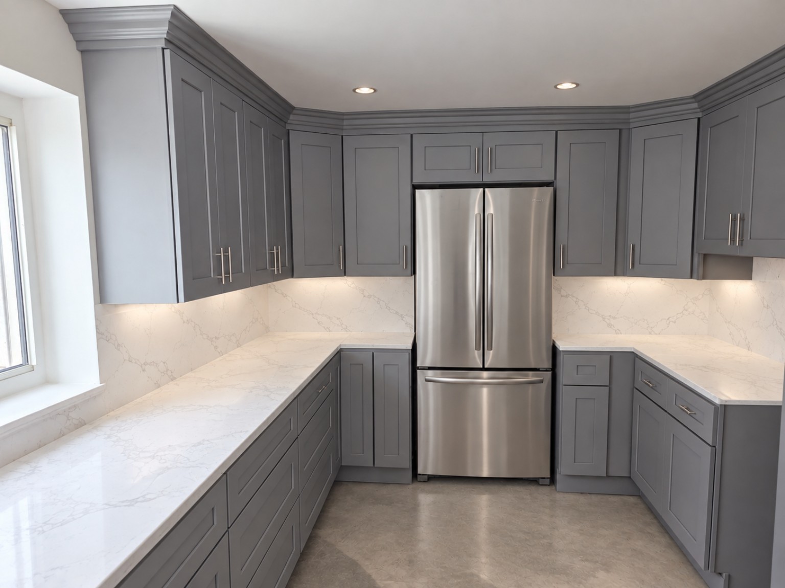Completed grey Shaker kitchen with crown molding, white quartz countertops and stainless French-door refrigerator