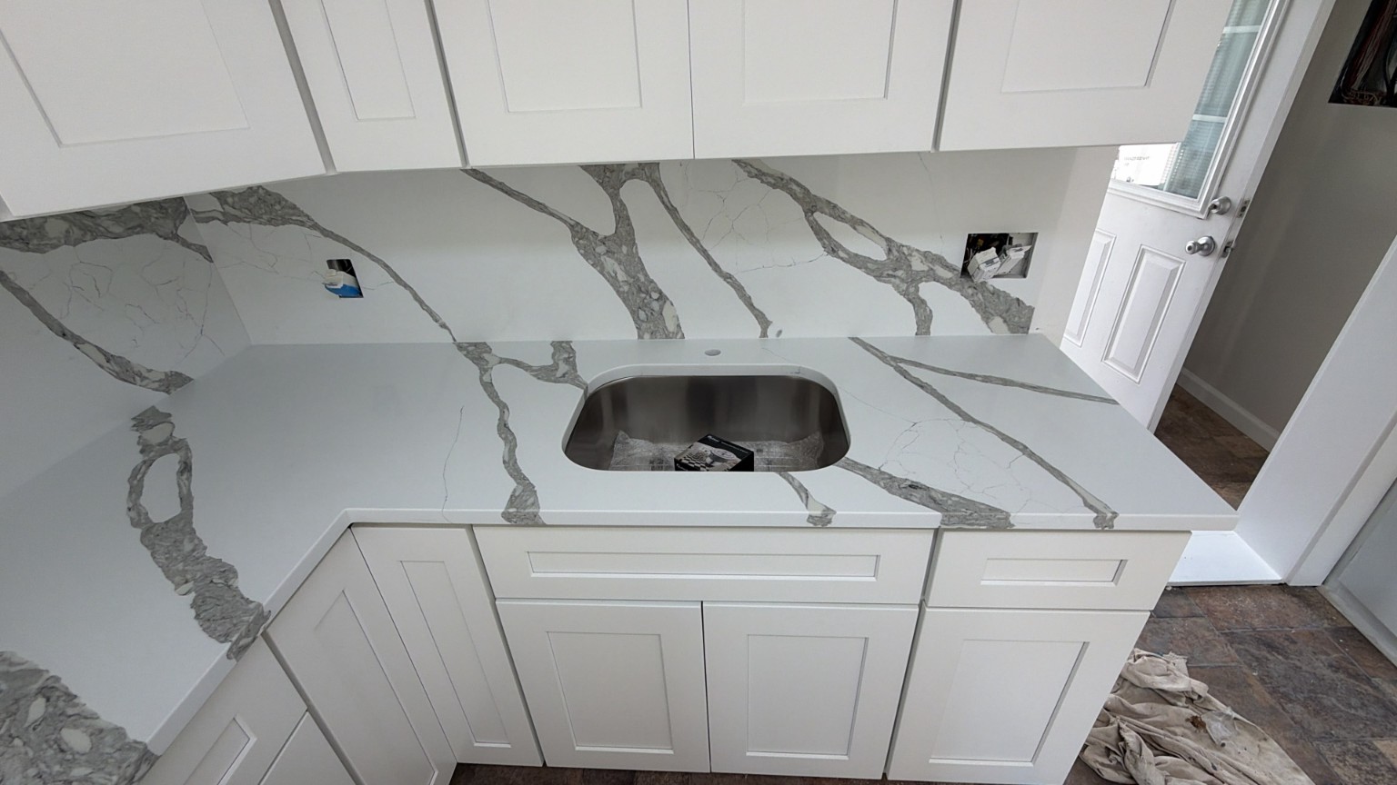 Completed white Shaker cabinets with dramatic quartz countertop and backsplash