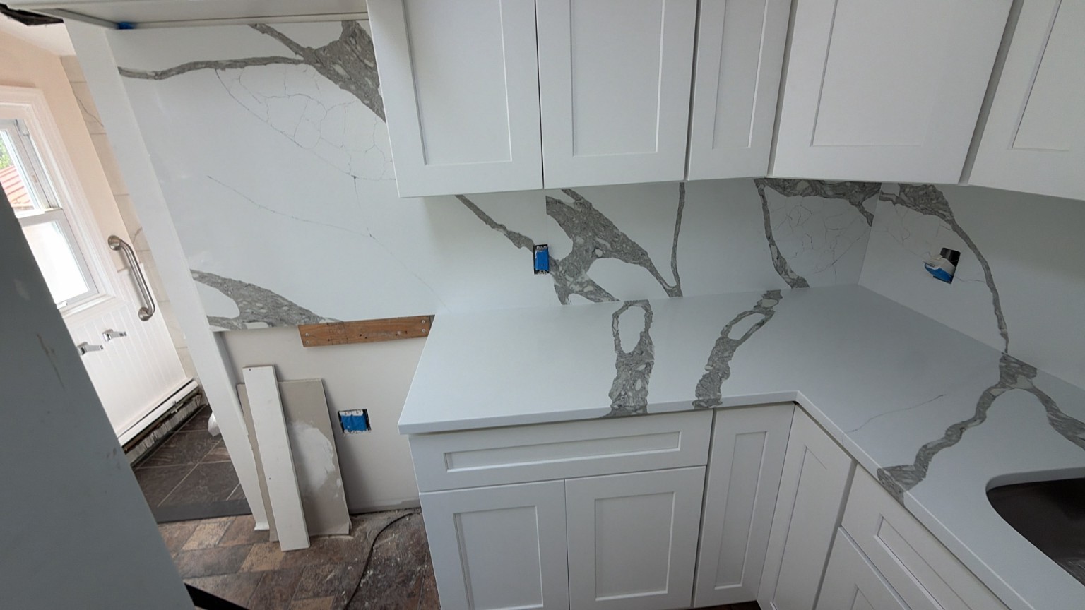 Completed full-height quartz backsplash with white Shaker cabinets