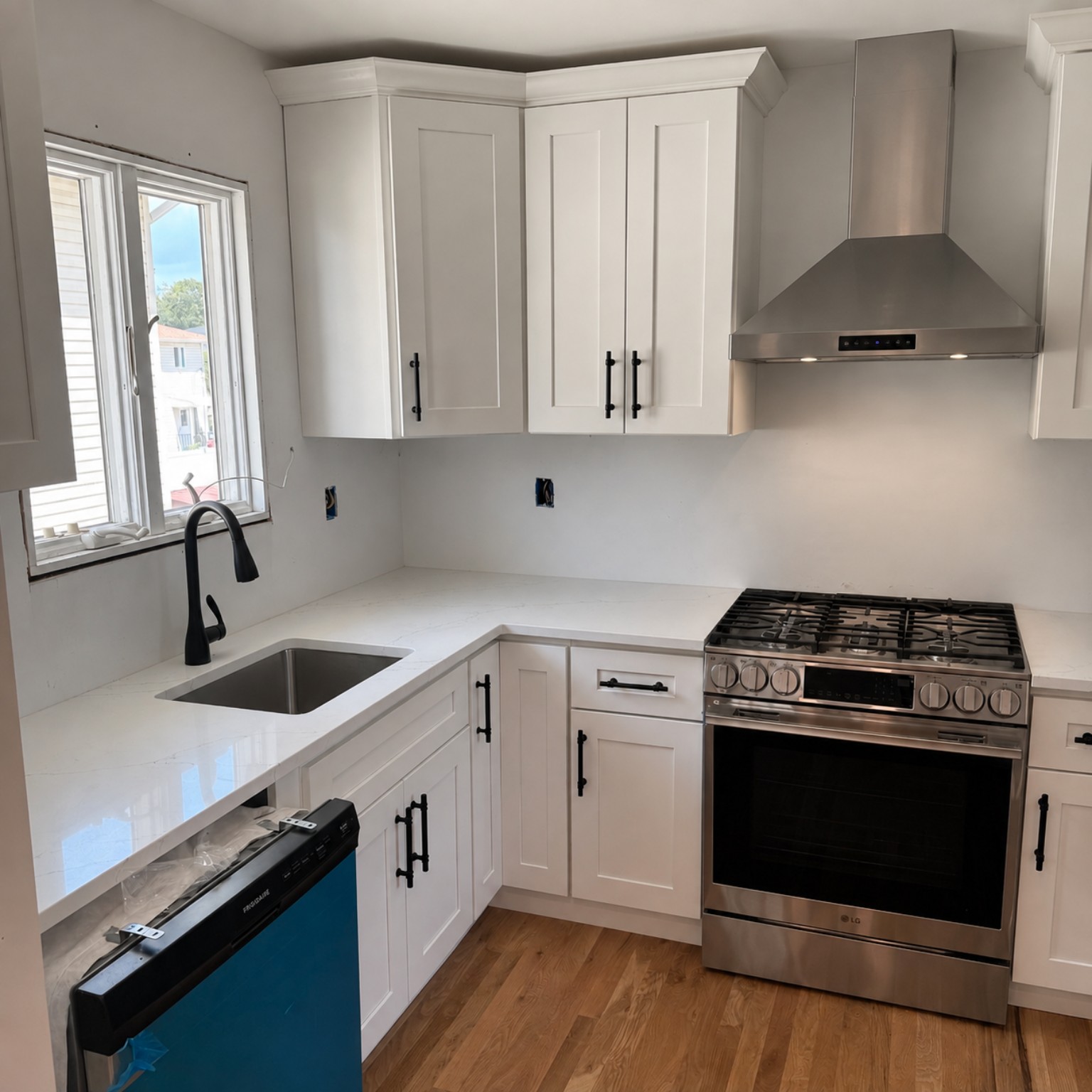 Completed white Shaker kitchen with quartz countertops and stainless appliances